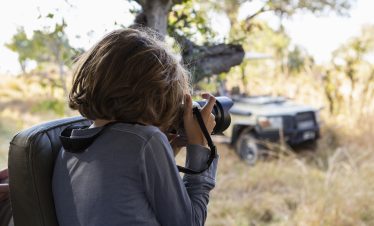 Okavango Delta,Botswana,young boy using a large camera during a jeep drive on safari